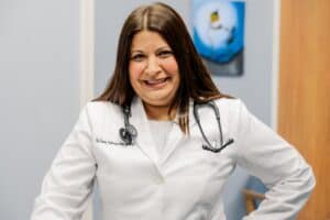 Dr Samia in a white coat with a stethoscope around her neck.